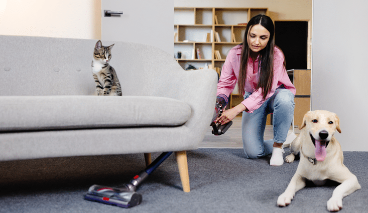 chica limpiando casa con aspiradora, mientras esa un un perro y un gato